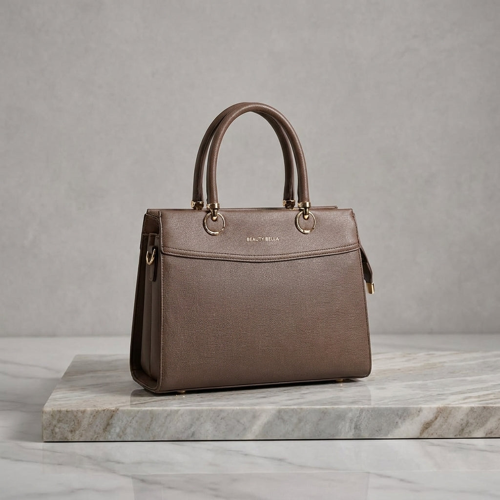 A structured brown leather handbag with double top handles and gold-tone hardware, displayed on a marble slab against a textured gray background.